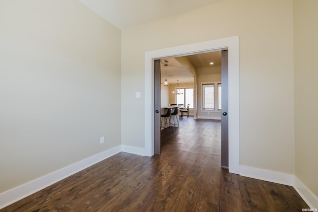 interior space with a chandelier, dark wood-style flooring, and baseboards