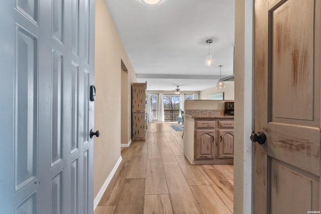 corridor featuring baseboards and light wood-type flooring