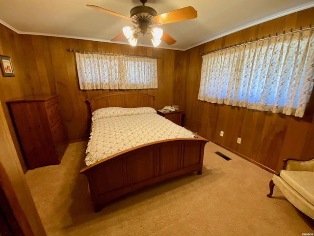 bedroom featuring light carpet, crown molding, a ceiling fan, and wooden walls