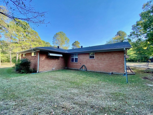 back of property featuring a yard and brick siding