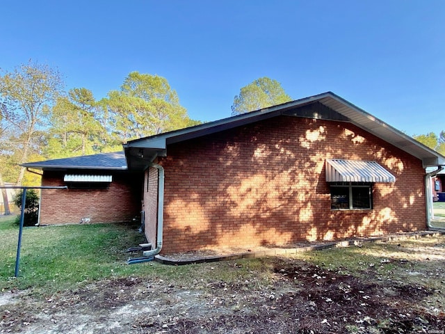 view of side of property featuring brick siding and a yard