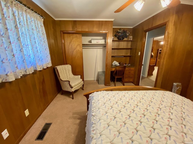 bedroom with light colored carpet, wood walls, visible vents, ornamental molding, and a closet