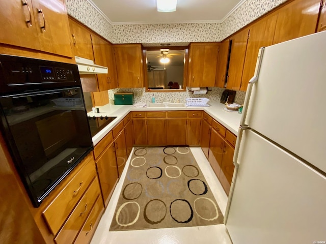 kitchen featuring light countertops, brown cabinets, black appliances, and wallpapered walls