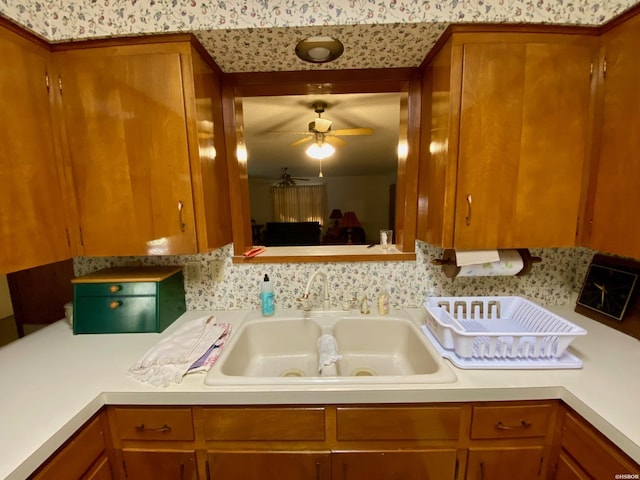 kitchen with brown cabinetry, light countertops, and a sink