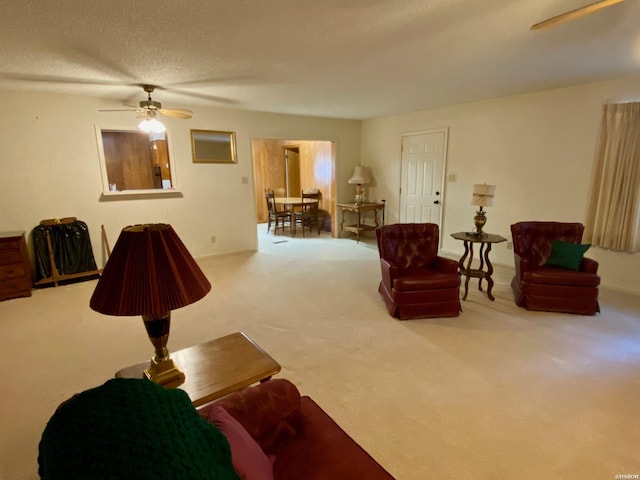 living room with a ceiling fan, carpet flooring, and a textured ceiling