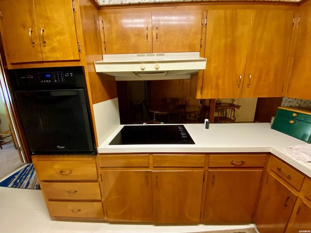 kitchen with black appliances, under cabinet range hood, light countertops, and brown cabinetry