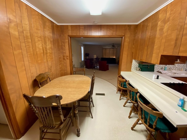 dining room with wooden walls, ornamental molding, and carpet flooring