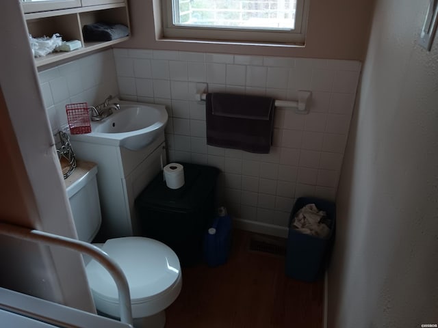 half bath featuring toilet, visible vents, tile walls, and vanity