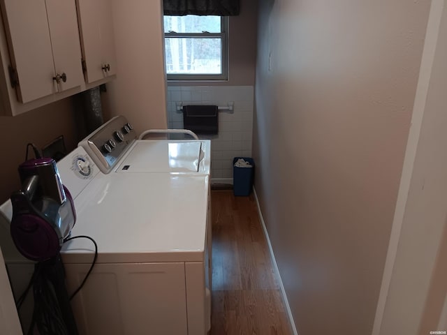 washroom with cabinet space, tile walls, washing machine and clothes dryer, and wood finished floors