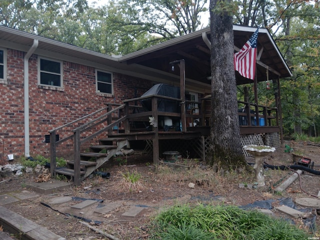 exterior space with a deck, brick siding, and stairway