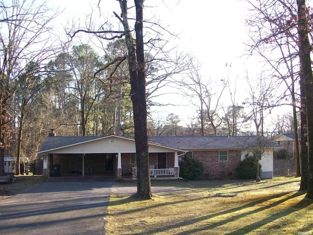 ranch-style house featuring driveway, brick siding, crawl space, a carport, and a front yard