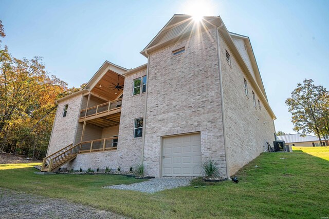 view of property exterior with a balcony, a garage, brick siding, a yard, and stairway