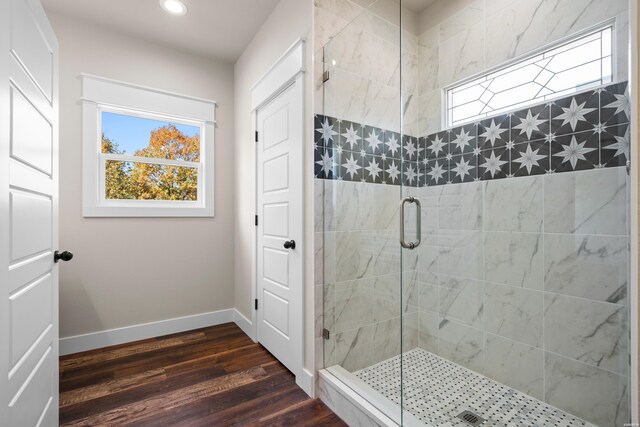 full bath with a healthy amount of sunlight, a stall shower, wood finished floors, and baseboards