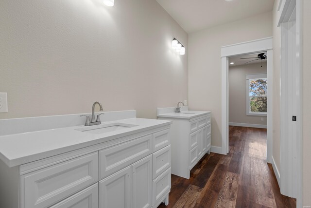 bathroom featuring two vanities, a sink, baseboards, and wood finished floors