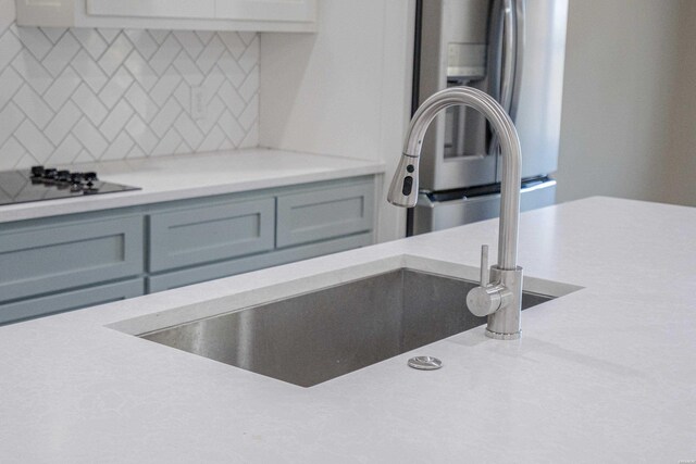 interior details featuring light countertops, gray cabinets, a sink, and decorative backsplash