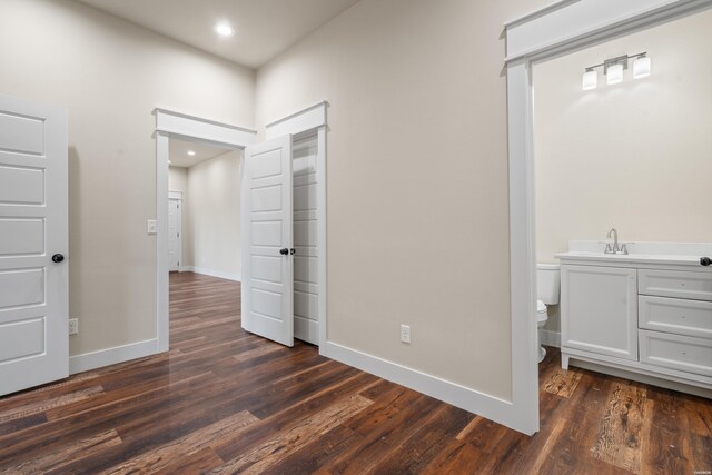 unfurnished bedroom with baseboards, dark wood finished floors, a sink, and recessed lighting