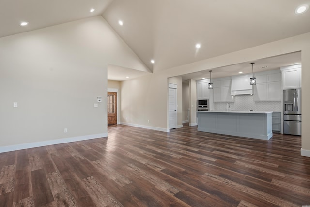 unfurnished living room with high vaulted ceiling, dark wood-style flooring, recessed lighting, and baseboards