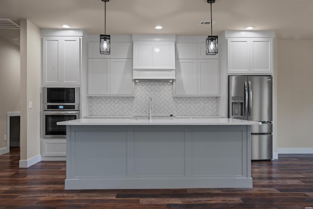 kitchen featuring white cabinets, stainless steel appliances, a center island with sink, and pendant lighting