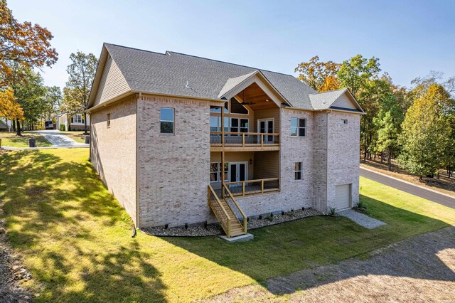 back of property featuring a balcony, a shingled roof, brick siding, a yard, and french doors