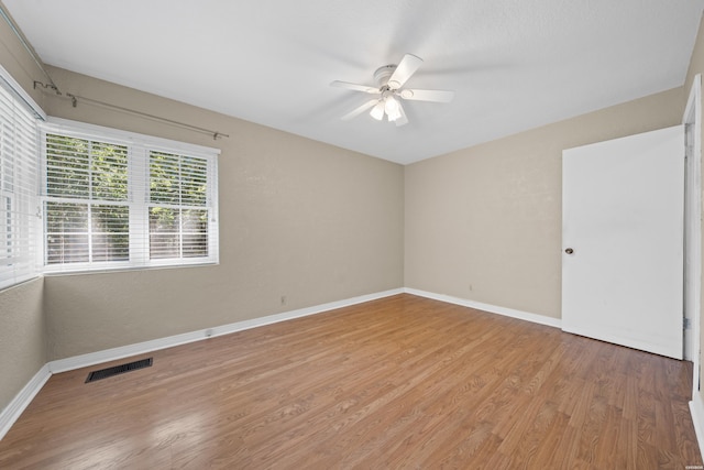 spare room with a ceiling fan, baseboards, visible vents, and wood finished floors