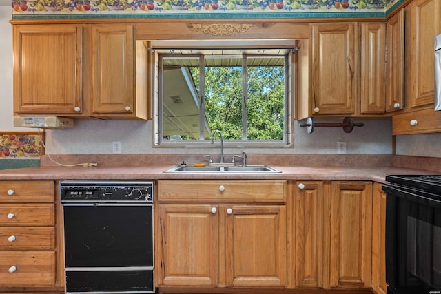 kitchen featuring brown cabinetry, light countertops, a sink, and black appliances