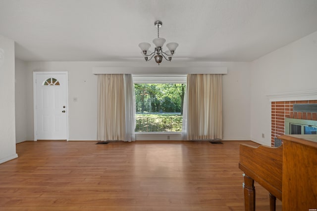 unfurnished living room featuring baseboards, a tile fireplace, wood finished floors, and an inviting chandelier