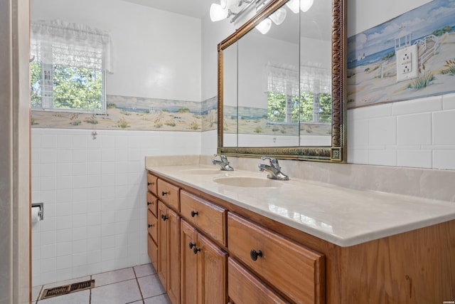 bathroom with double vanity, wainscoting, tile patterned floors, a sink, and tile walls