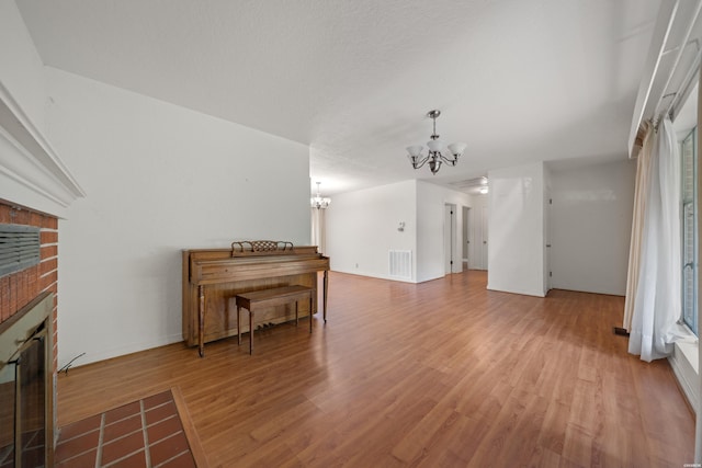 living room with baseboards, visible vents, wood finished floors, a fireplace, and a notable chandelier