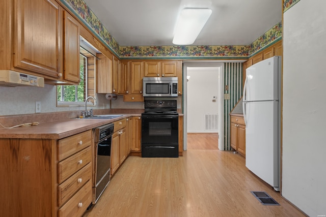 kitchen featuring a sink, visible vents, freestanding refrigerator, black electric range oven, and stainless steel microwave