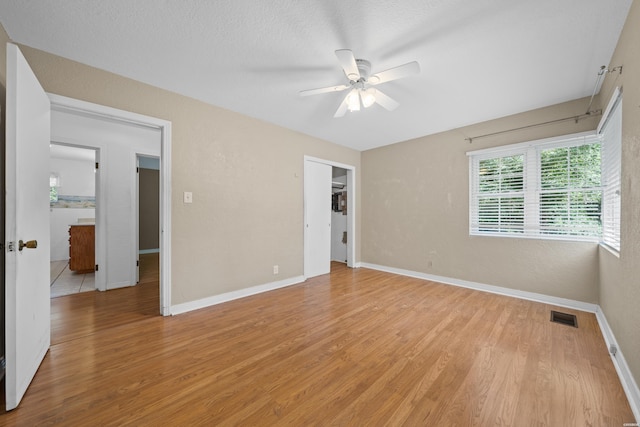 empty room featuring baseboards, visible vents, ceiling fan, a textured ceiling, and light wood-type flooring