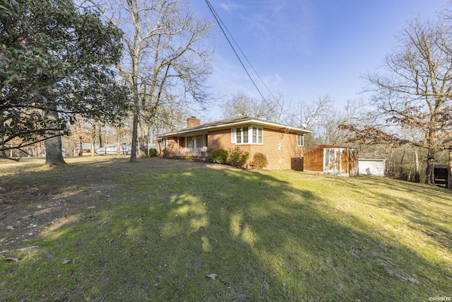 view of side of property with a chimney, a lawn, and brick siding