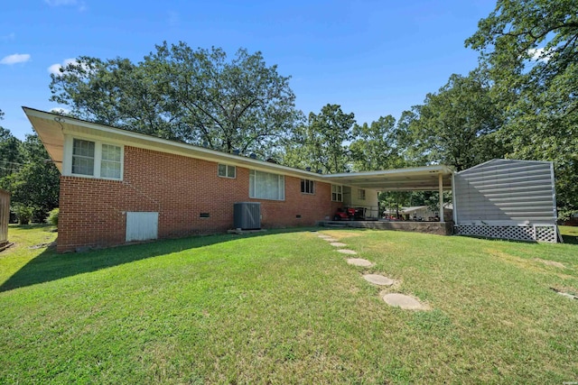 rear view of house with central AC unit, a lawn, an attached carport, crawl space, and brick siding