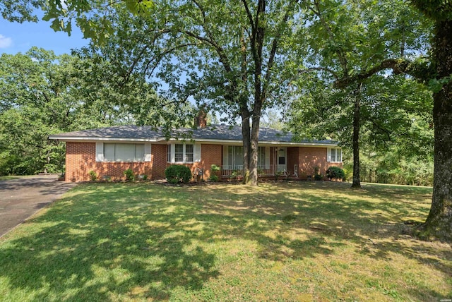 ranch-style house featuring brick siding, a front lawn, and a chimney