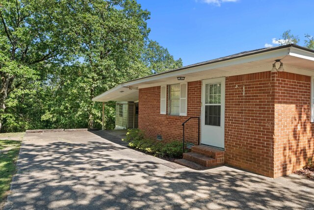 view of front of home featuring entry steps, crawl space, driveway, and brick siding