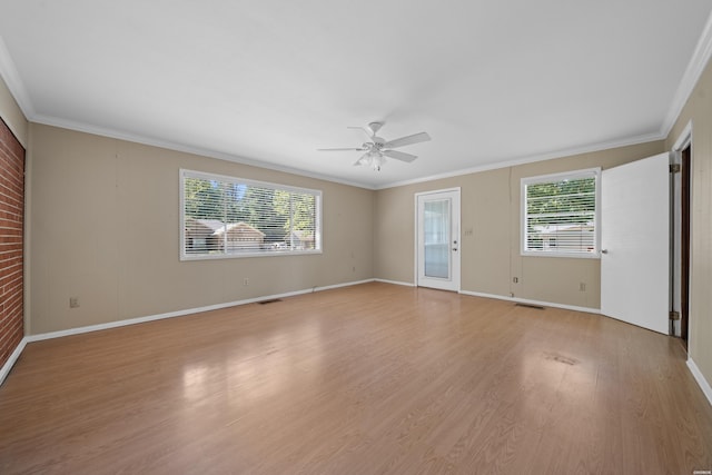 spare room with crown molding, visible vents, ceiling fan, light wood-type flooring, and baseboards