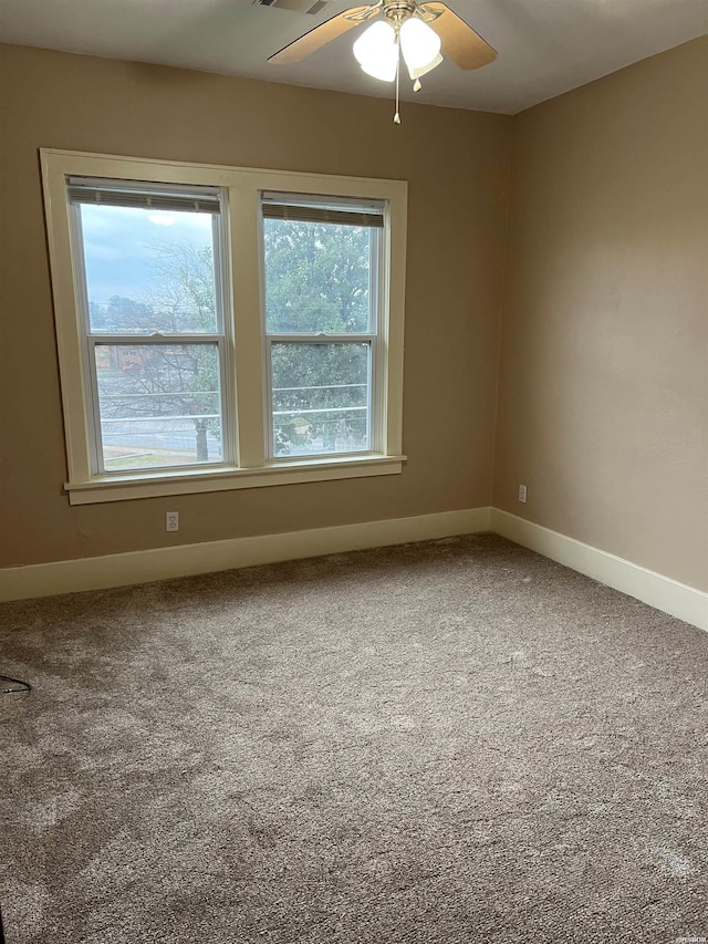 carpeted spare room with a ceiling fan and baseboards