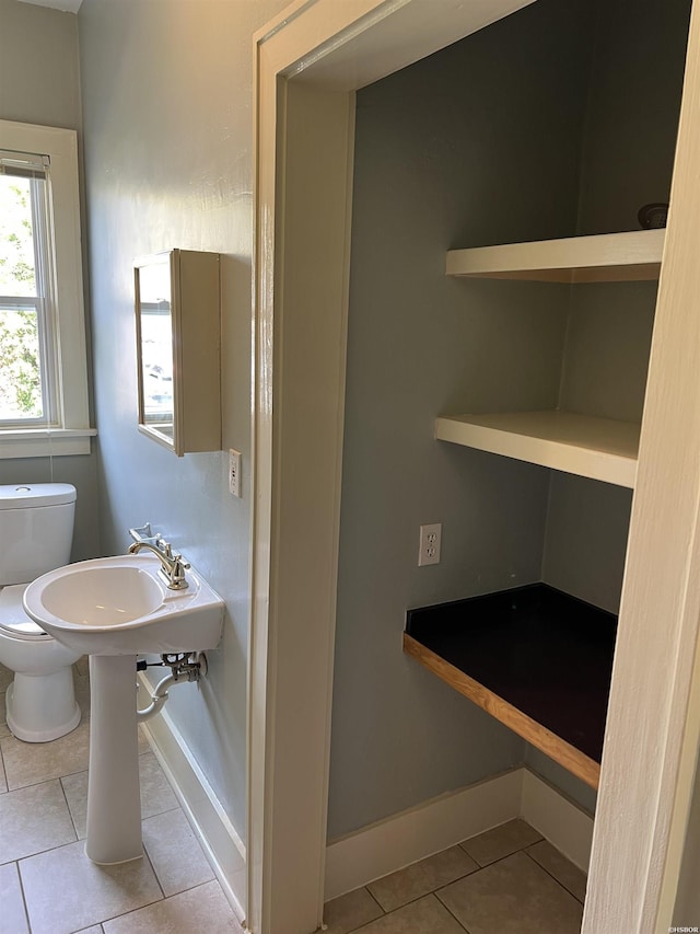 half bathroom with tile patterned flooring, baseboards, and toilet