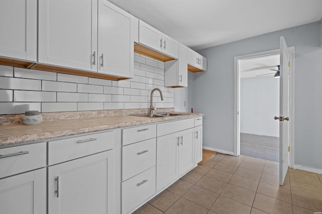 kitchen with light tile patterned floors, baseboards, a sink, decorative backsplash, and white cabinetry