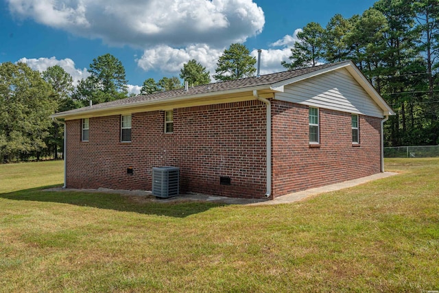 view of side of home with a lawn, brick siding, and central AC