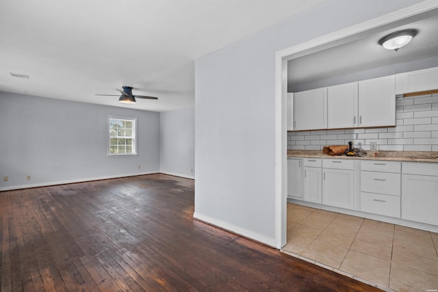 interior space with visible vents, backsplash, a ceiling fan, and white cabinetry