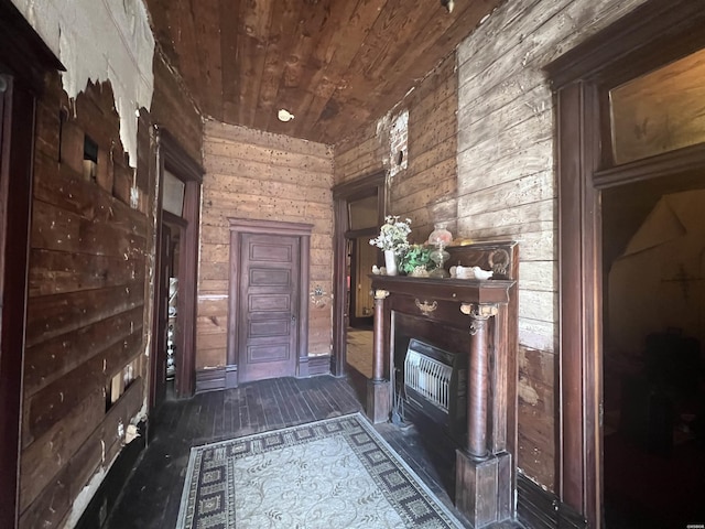 interior space with dark wood finished floors, wooden ceiling, a fireplace, and wood walls