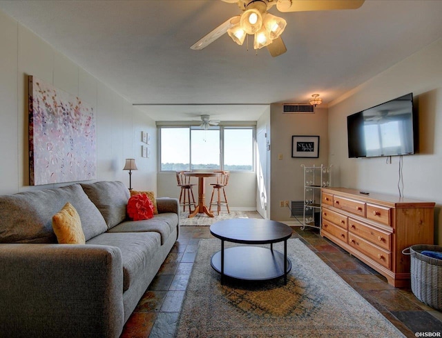 living room featuring a ceiling fan, stone tile floors, and visible vents