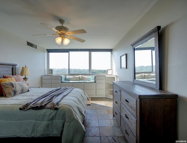 bedroom with stone tile floors, visible vents, and a ceiling fan