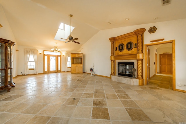 unfurnished living room featuring visible vents, lofted ceiling with skylight, a notable chandelier, a fireplace, and baseboards