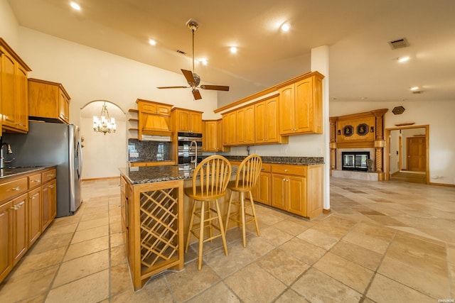 kitchen featuring visible vents, open shelves, double oven, ceiling fan with notable chandelier, and a kitchen island with sink