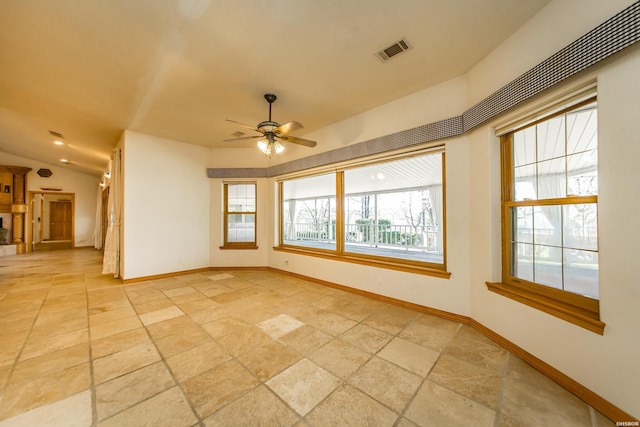 unfurnished room featuring visible vents, baseboards, lofted ceiling, stone tile flooring, and a ceiling fan