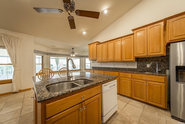 kitchen featuring vaulted ceiling, a sink, stainless steel fridge, and white dishwasher