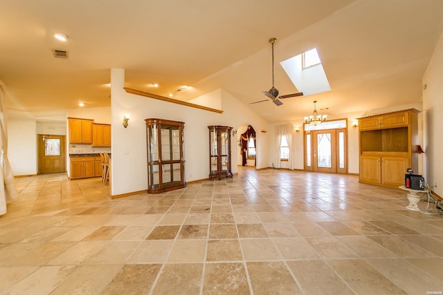 unfurnished living room with baseboards, visible vents, high vaulted ceiling, a skylight, and a notable chandelier