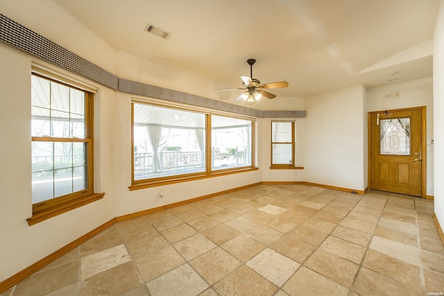 empty room with visible vents, baseboards, stone tile floors, and a ceiling fan