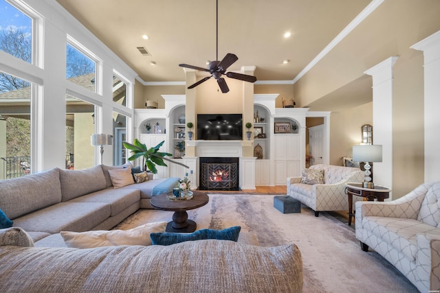 living area featuring ornamental molding, a high ceiling, a fireplace with flush hearth, and visible vents